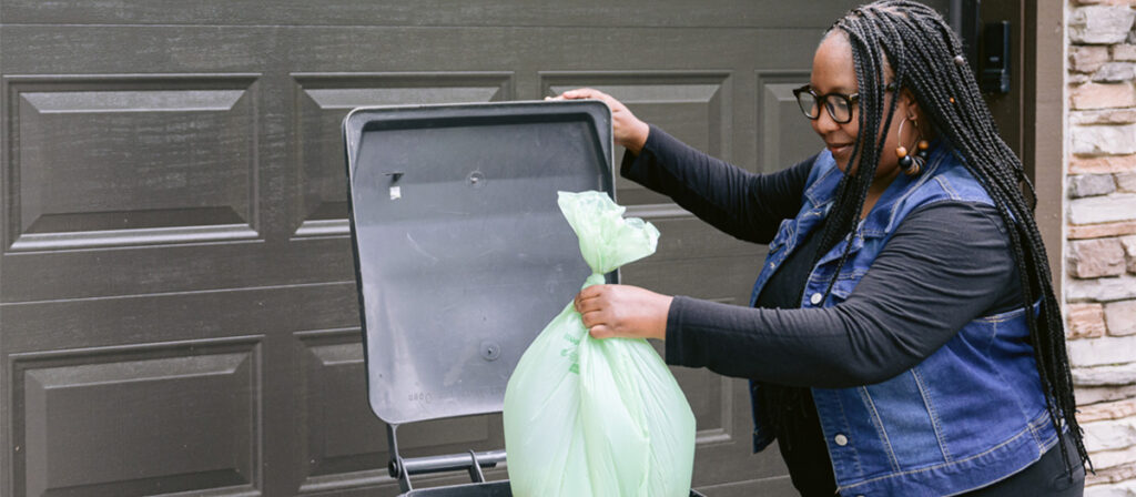 Person dropping food scraps bag into trash cart